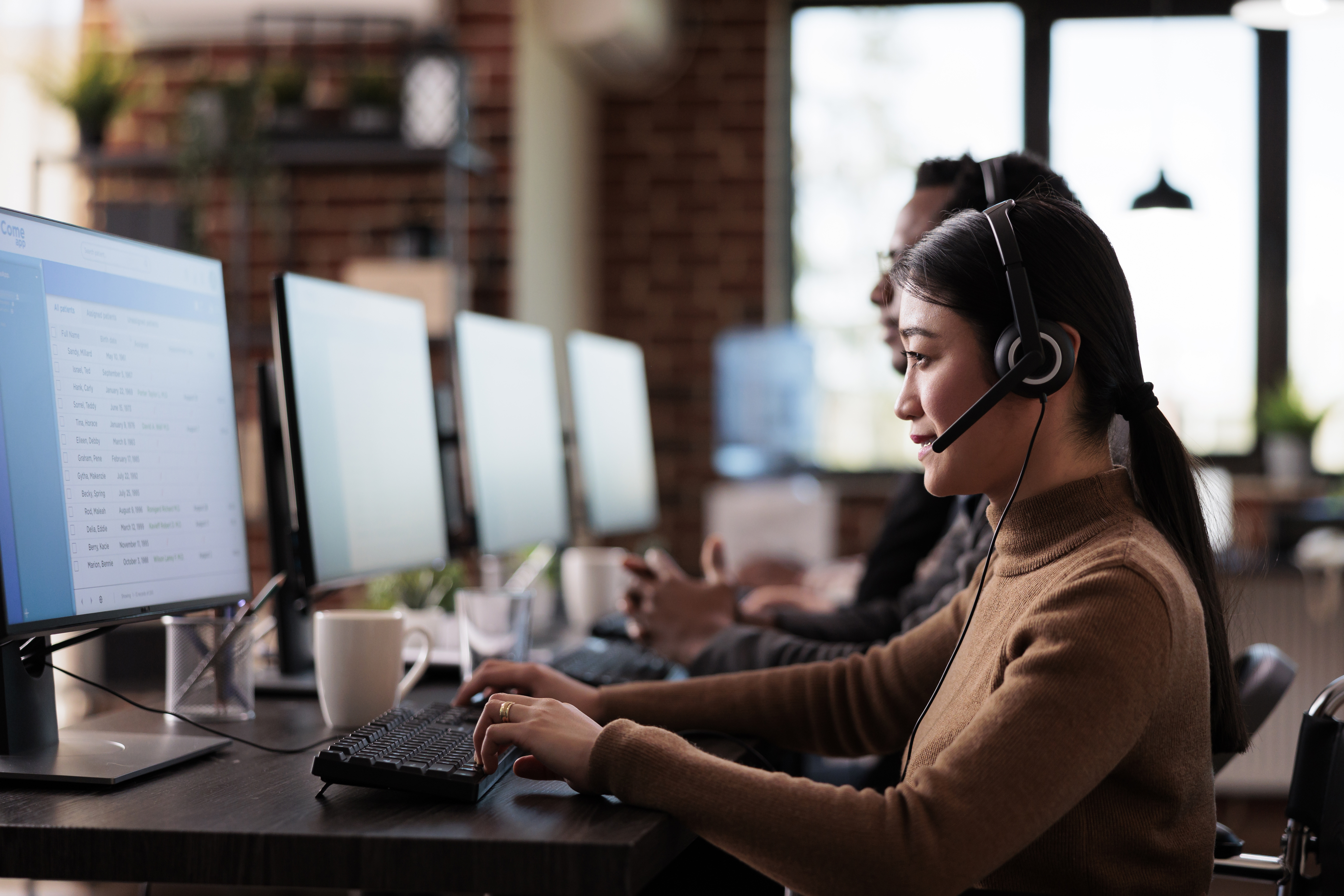 Technical support specialists using computers and headsets in a modern office environment