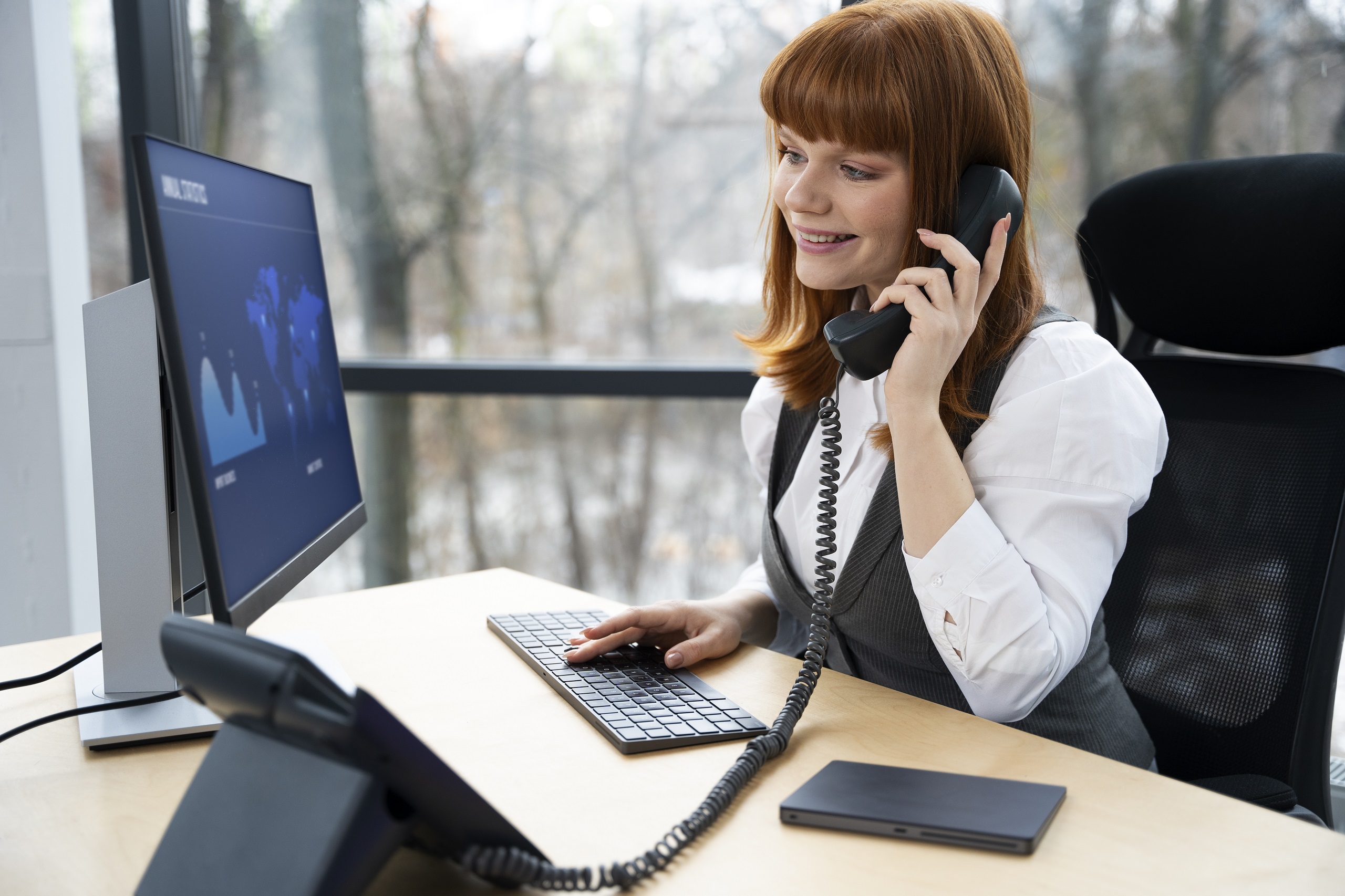 Person answering phone call while working at computer desk