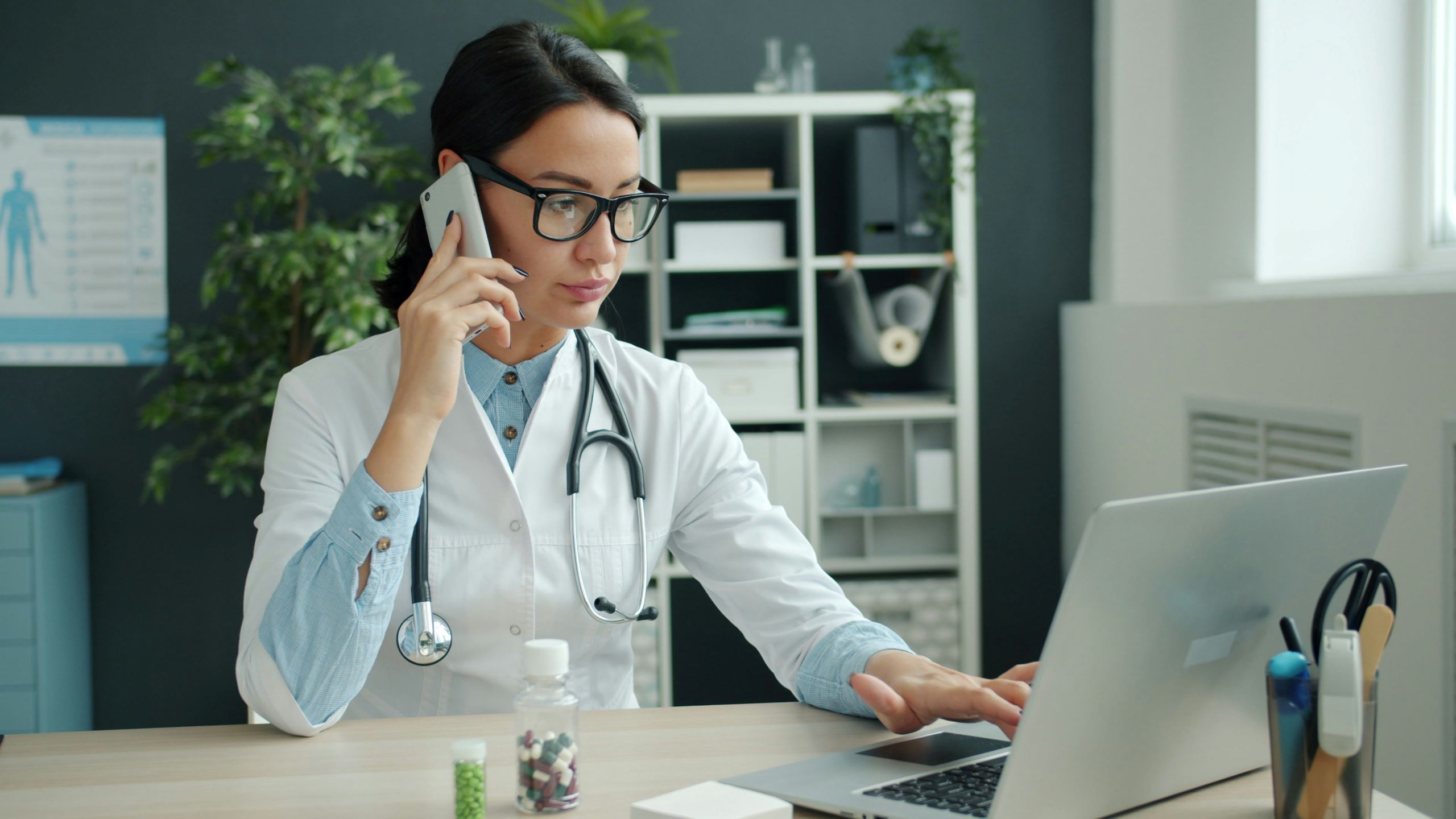 Medical professional having phone call in front of laptop.